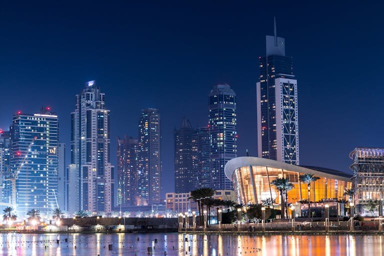 Stunning view of Dubai's illuminated skyline with modern skyscrapers reflecting on water at night.