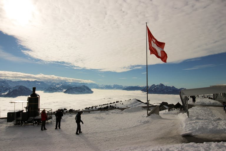 Majestic snowy view from Rigi Kulm, Switzerland, with Swiss flag and mountains.