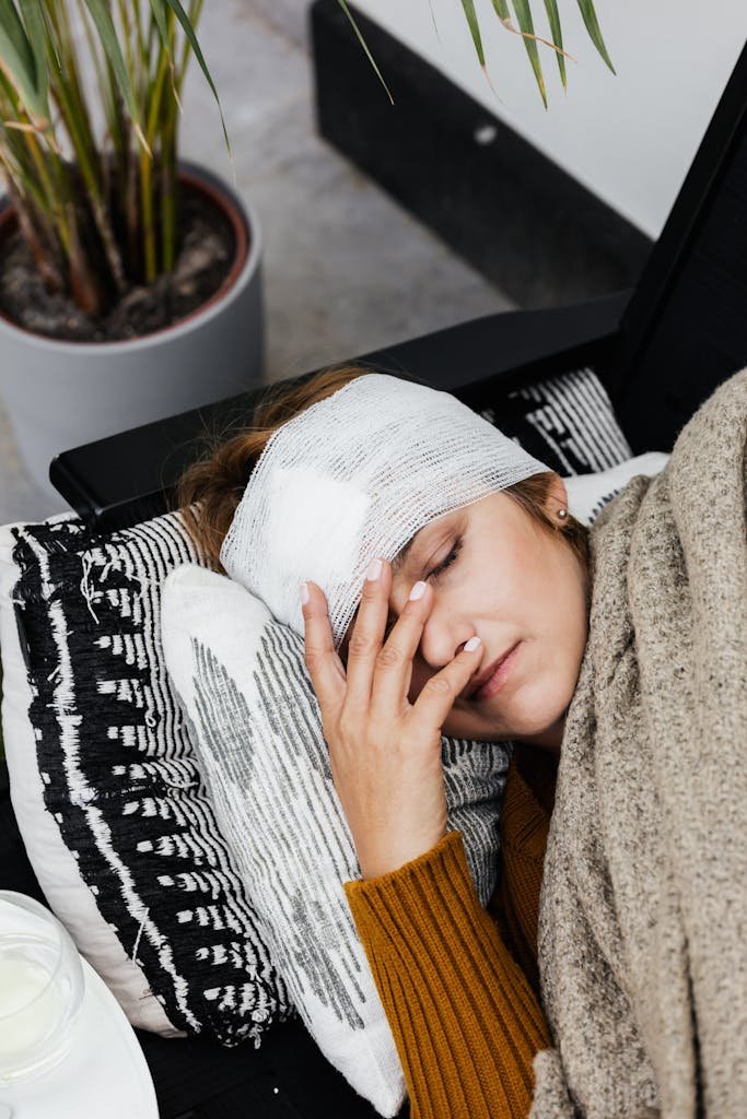 A woman with a head injury rests indoors, showcasing the warmth of a cozy, home environment.