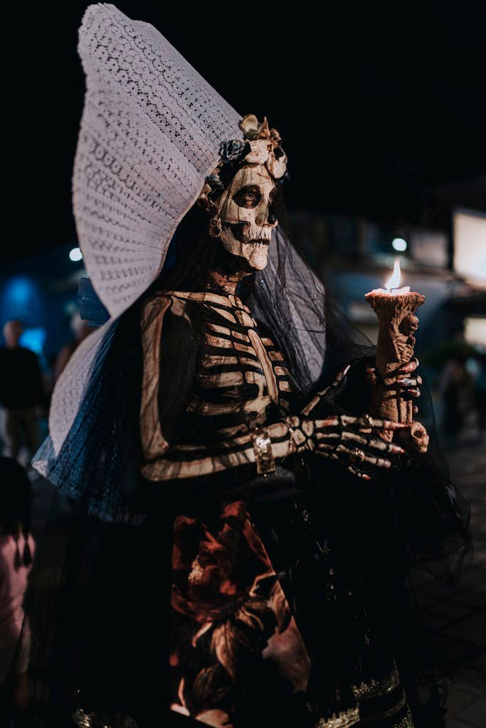 A woman in skeletal costume and makeup holds a candle during Day of the Dead festivities in Oaxaca.