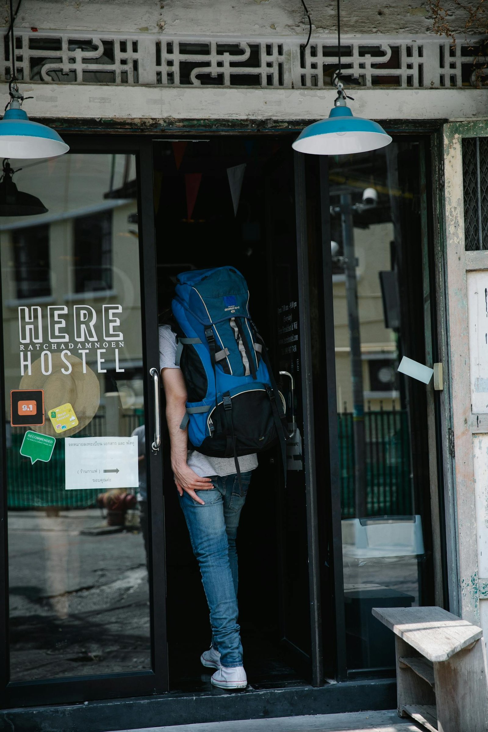 A backpacker entering a hostel through a glass door, featuring travel ambiance.