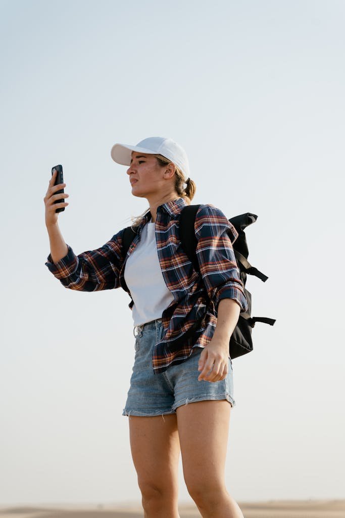 Young female traveler in desert taking a photo with her smartphone.