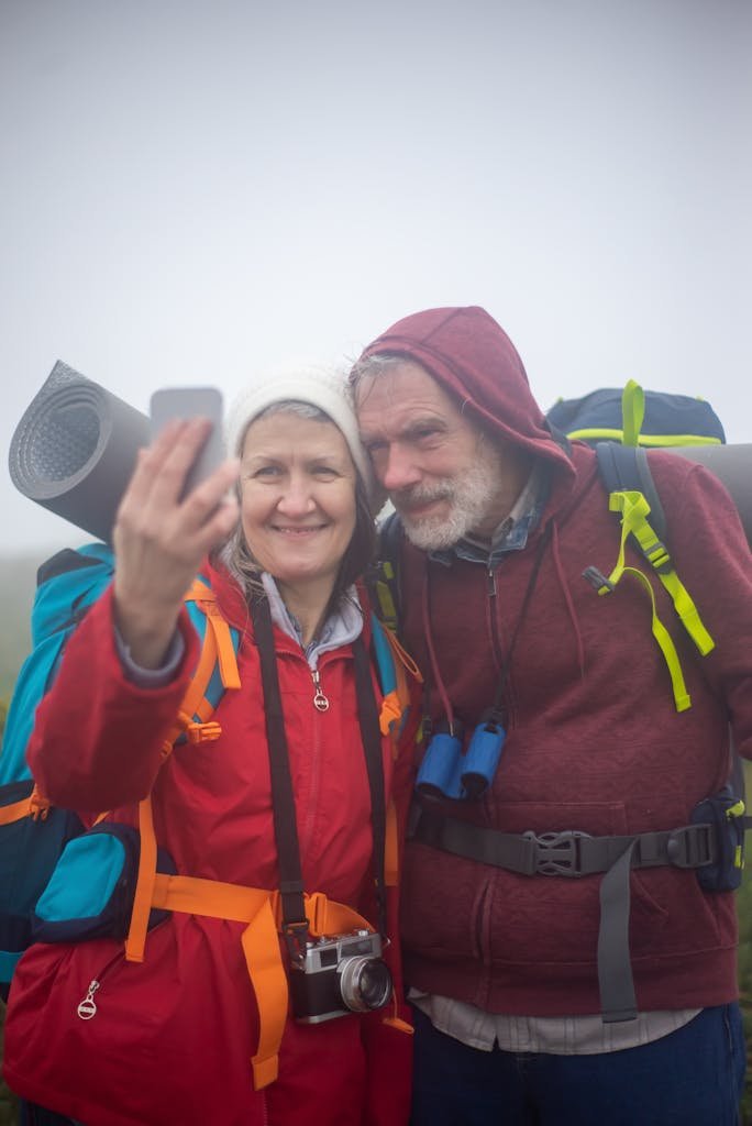 Elderly couple enjoying a hiking adventure in Portugal, capturing a selfie on a misty day.