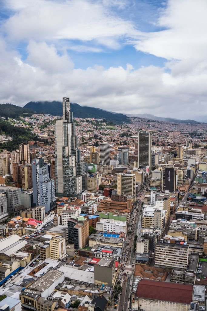 A bustling urban cityscape of Bogotá with iconic skyscrapers under a cloudy sky.