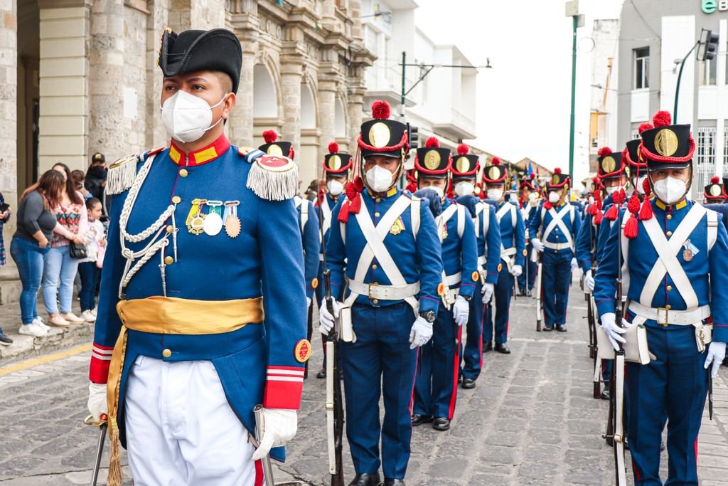 A group of uniformed soldiers in ceremonial attire march during a parade in Ecuador.