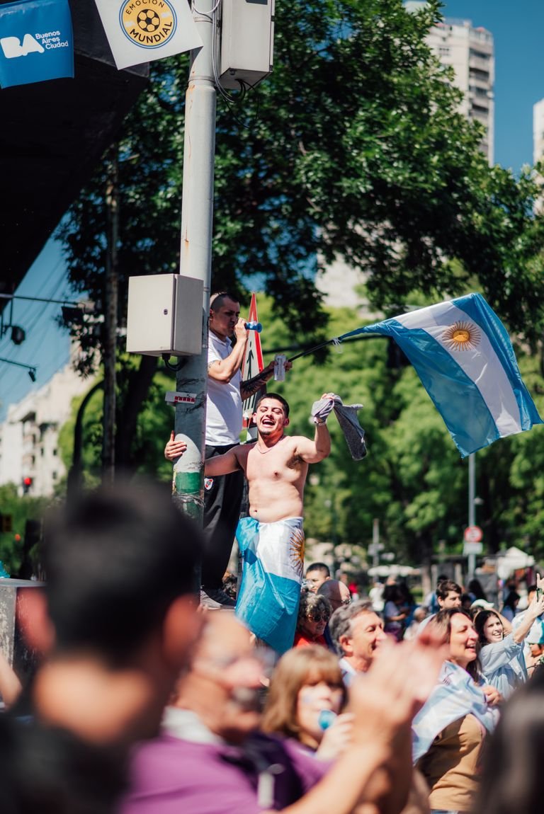 Joyful crowd in Buenos Aires celebrating with Argentine flags on a sunny day.