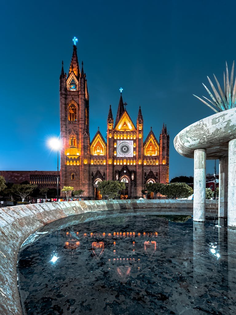Stunning night photograph of a cathedral in Guadalajara with illuminated facade and a reflective fountain foreground.