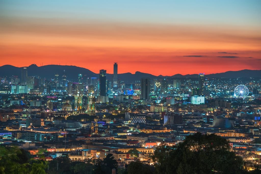 Stunning view of Puebla city's skyline with vibrant sunset colors and city lights.