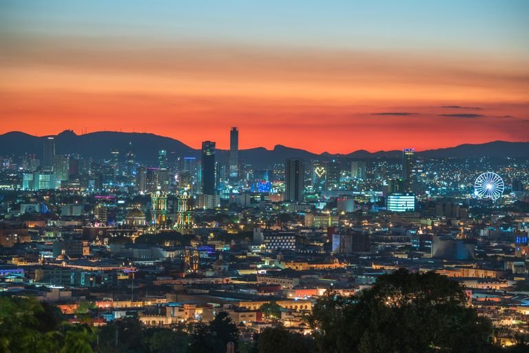 Stunning view of Puebla city's skyline with vibrant sunset colors and city lights.