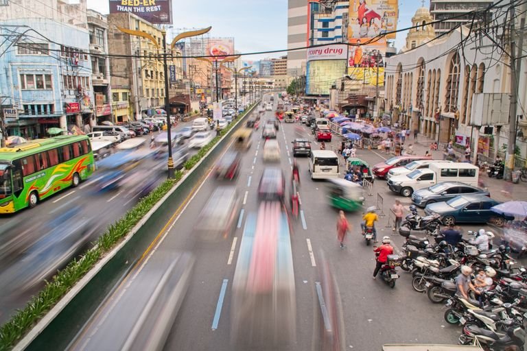 Vibrant daytime traffic in Manila city, showcasing bustling urban life and fast-moving vehicles.