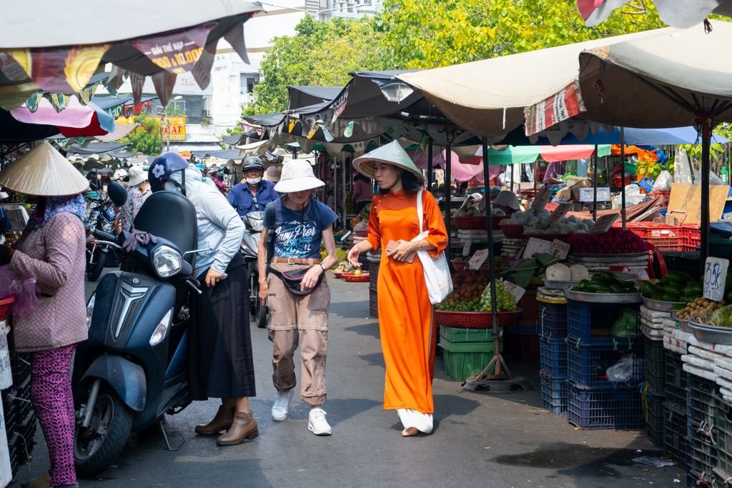 Colorful street market scene in Ho Chi Minh City with people shopping and vibrant produce stalls.