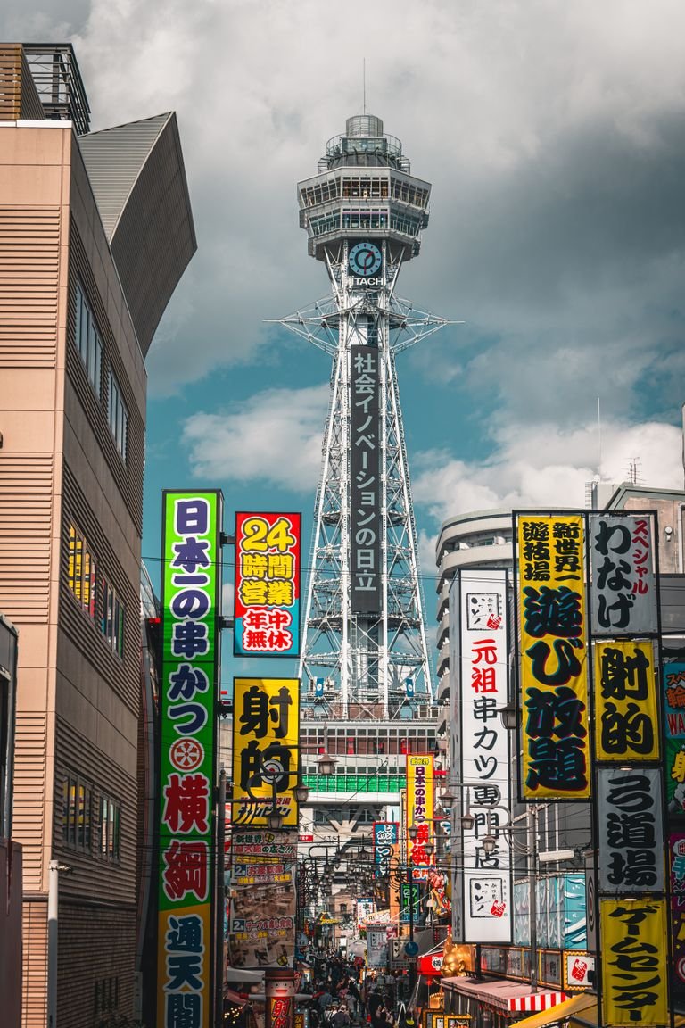 Dynamic scene of Osaka's bustling streets with Tsutenkaku Tower in view, capturing urban energy.