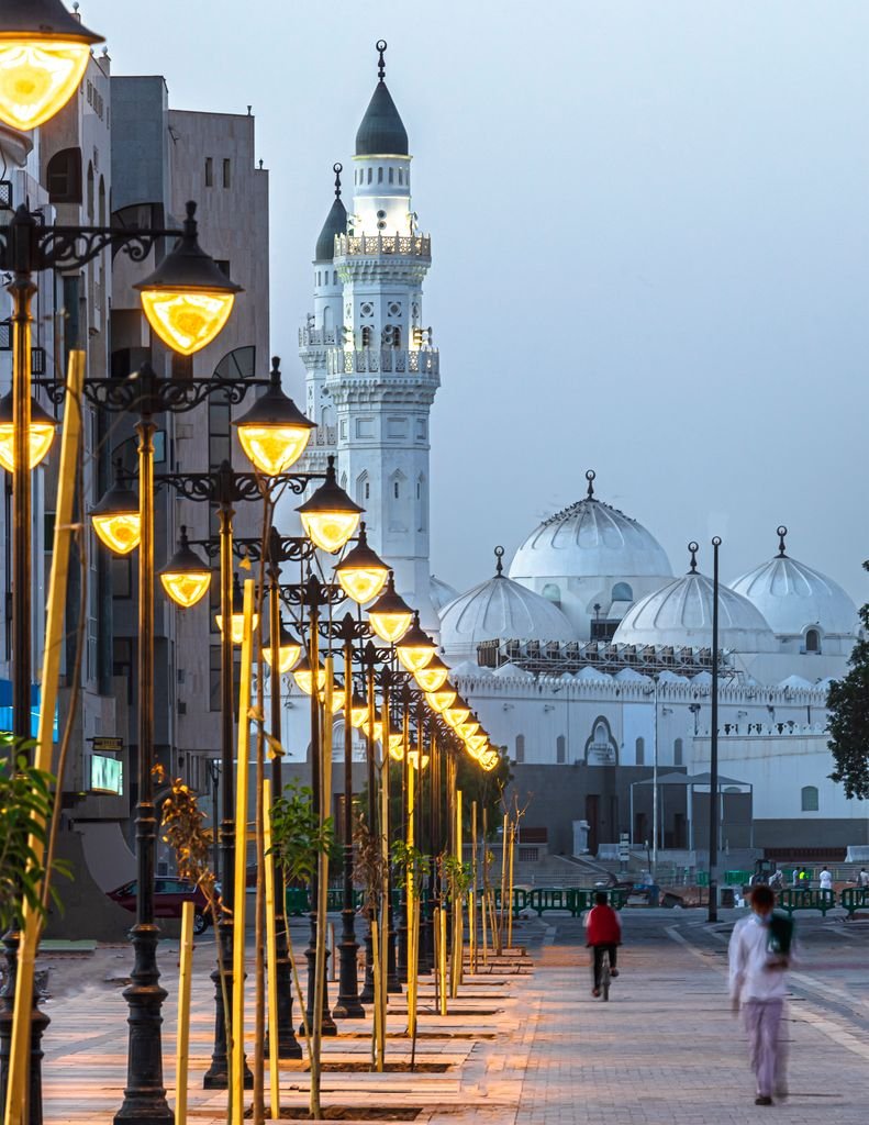 Illuminated street lights and iconic Quba Mosque domes in Riyadh, Saudi Arabia at dusk.