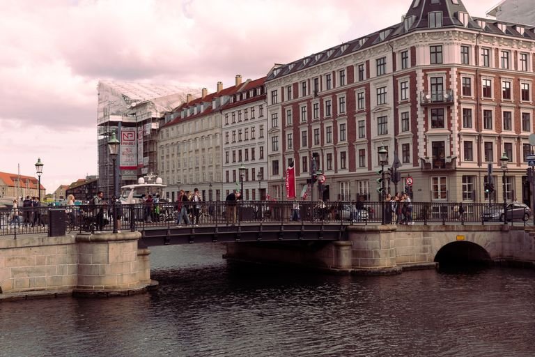 Scenic view of a historic bridge crossing a canal in a European old town, bustling with people.