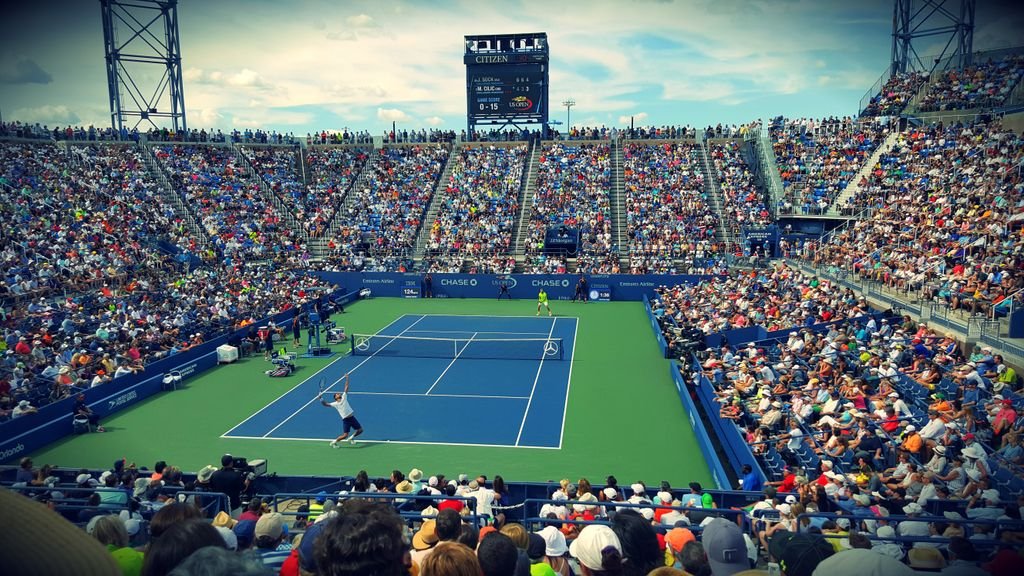 Thrilling tennis match at the US Open tennis with a full stadium of enthusiastic fans.