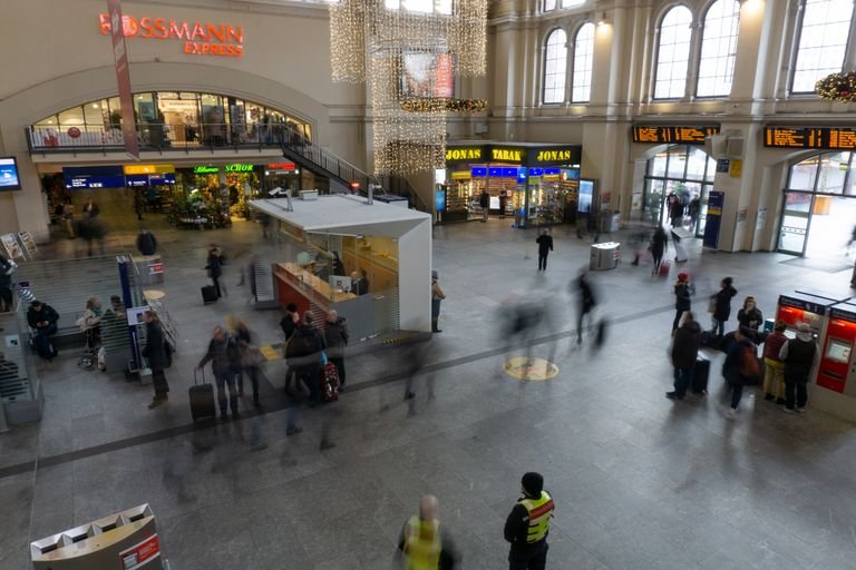 A bustling train station with blurred commuters, showcasing movement and travel.